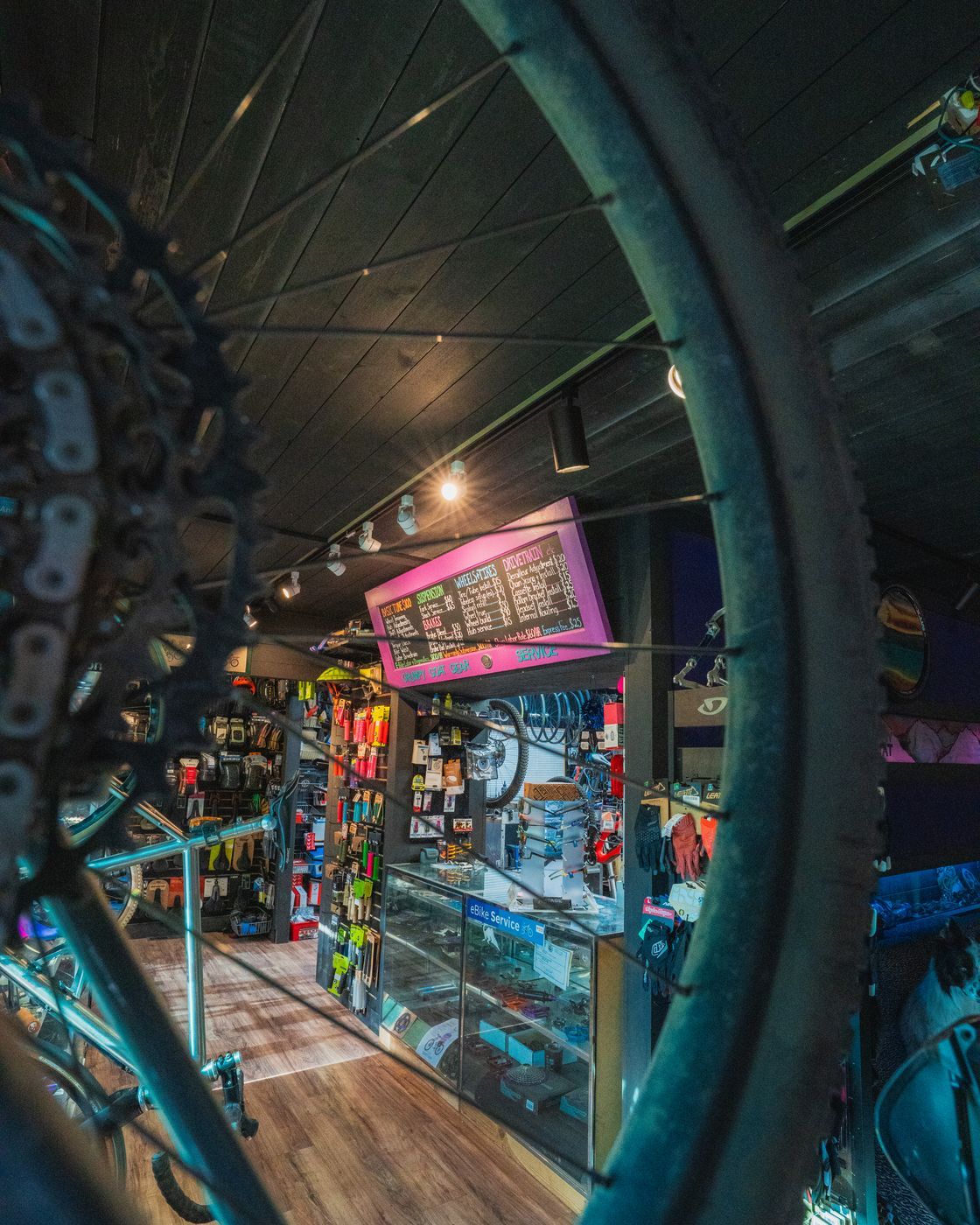 Parts and accessories on the shop floor, framed through a bike wheel